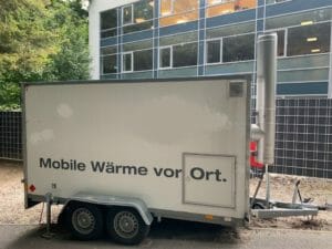 Gemietete weiße mobile Heizzentrale auf Anhänger vor Bürogebäude