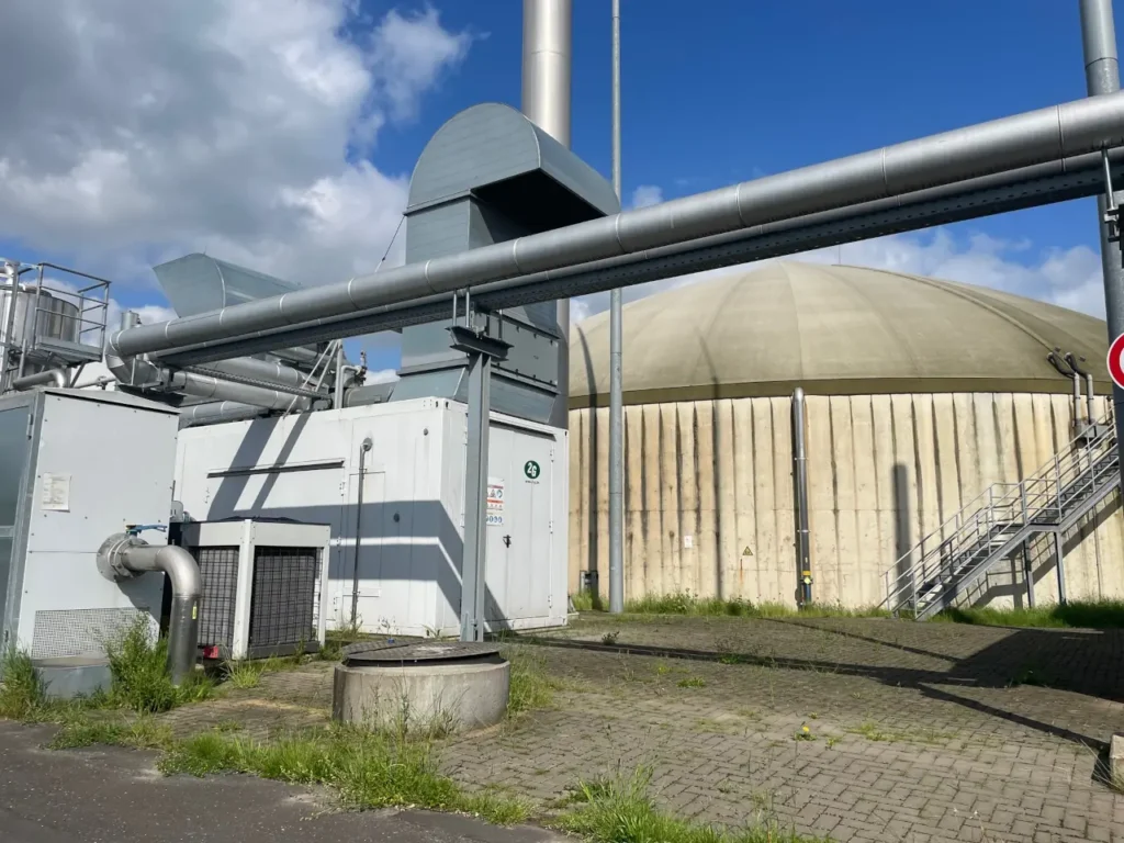 Biogas BHKW im Betrieb auf einem Hof neben einem Biogas Fermenter