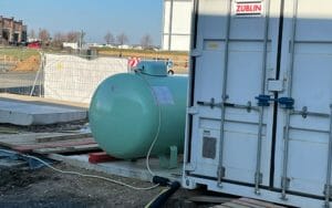 Ralgrüner Flüssiggastank auf einer Baustelle versorgt mobile Heizzentrale mit Brennstoff