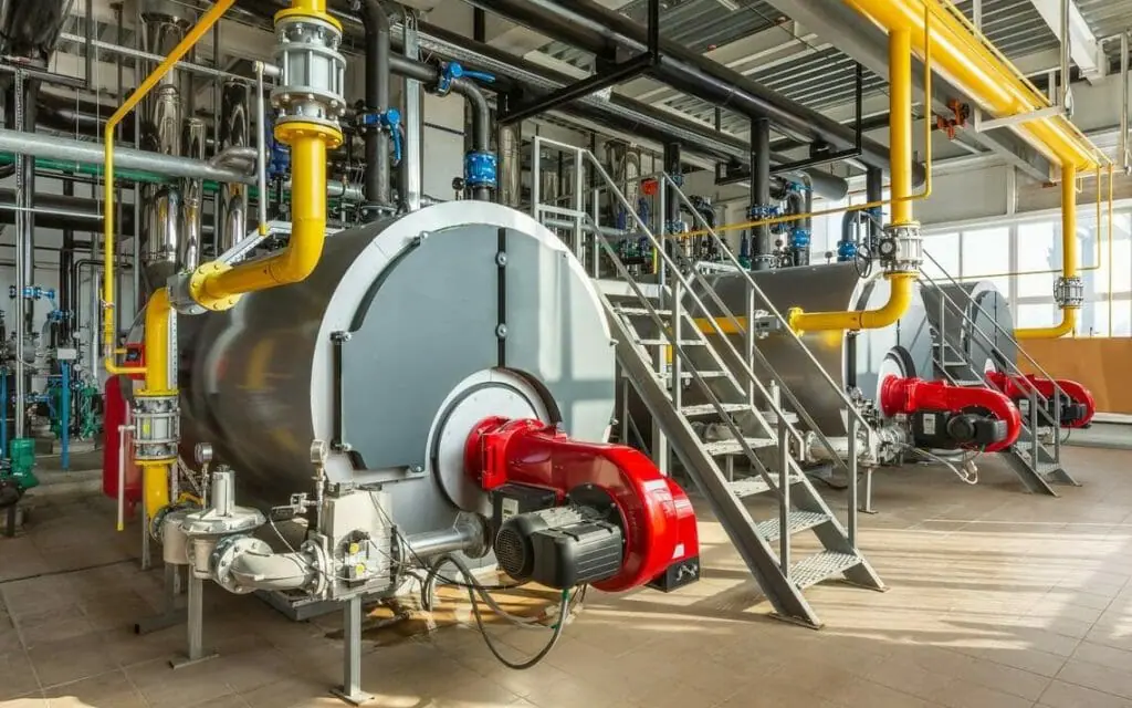 Drei an gelbe Rohre angeschlossene Dampfkessel zum Mieten arbeiten in einer Industrieanlage
