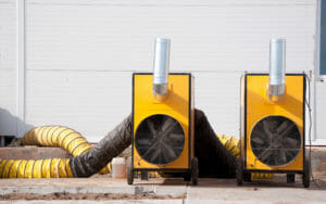 Gelbe Warmlufterzeuger führen warme Luft über Warmluftschläuche in das Gebäude