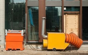 Mobiler Warmlufterzeuger und mobiler Öltank auf Baustelle mit Lufttransportschlauch