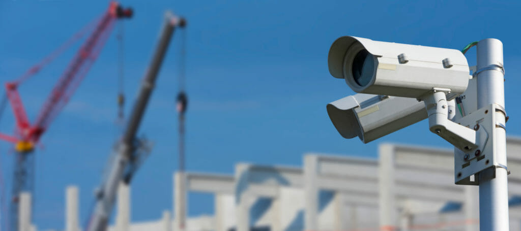 Baustellenueberwachung mit zwei Ueberwachungskameras auf einer Baustelle mit Kraenen im Hintergrund