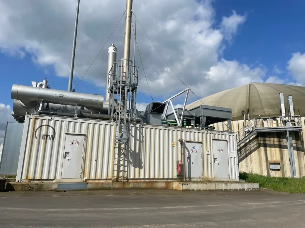 Biogas BHKW neben einem Biogas Fermenter auf einem Hof