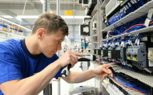 Elektriker montiert Schaltschrank in einer Industriehalle