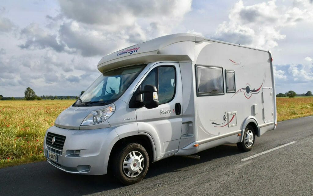 Weißes Wohnmobil auf Landstraße mit Feld im Hintergrund