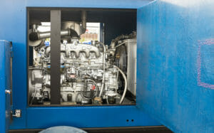 gemietetes blaues BHKW mit geöffneter Seitenklappe und freiem Blick auf den Motor