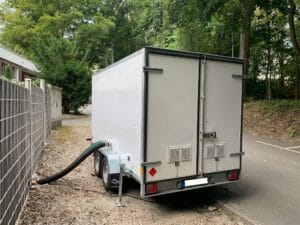 Mobile Heizzentrale mit bestehender Verschlauchung im Betrieb vor Gebaeude