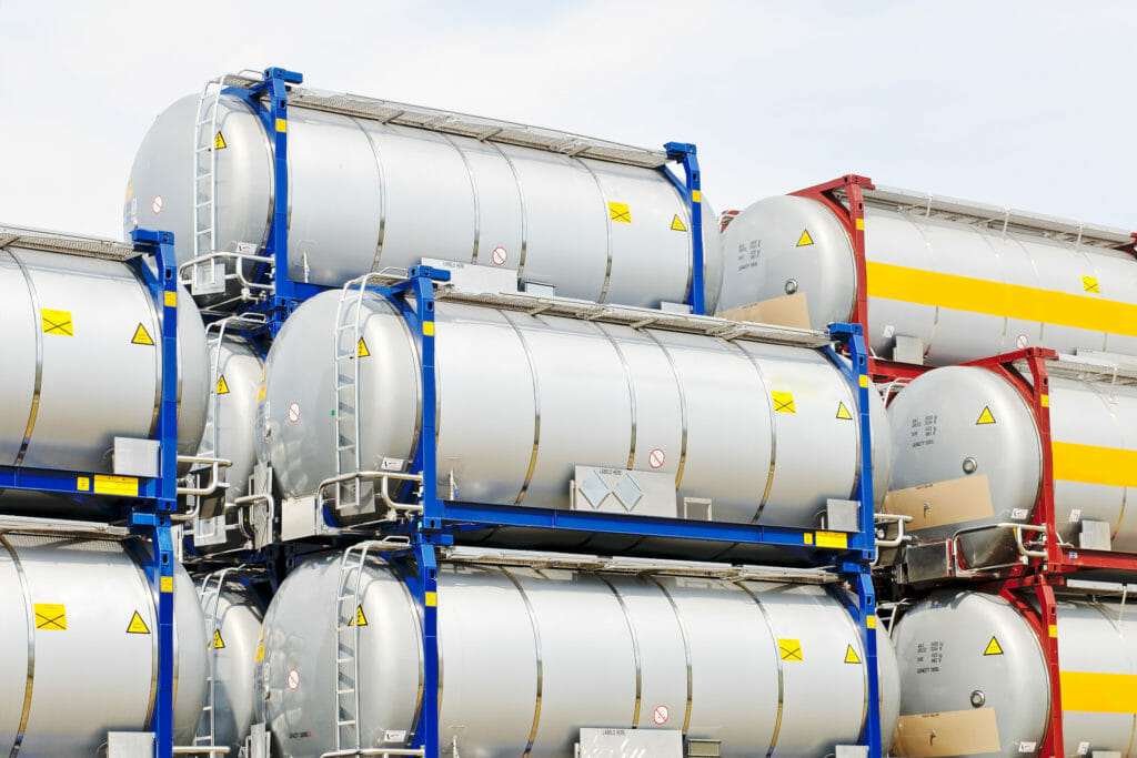 Verschiedene Tankcontainer uebereinander gestapelt in Industrielager