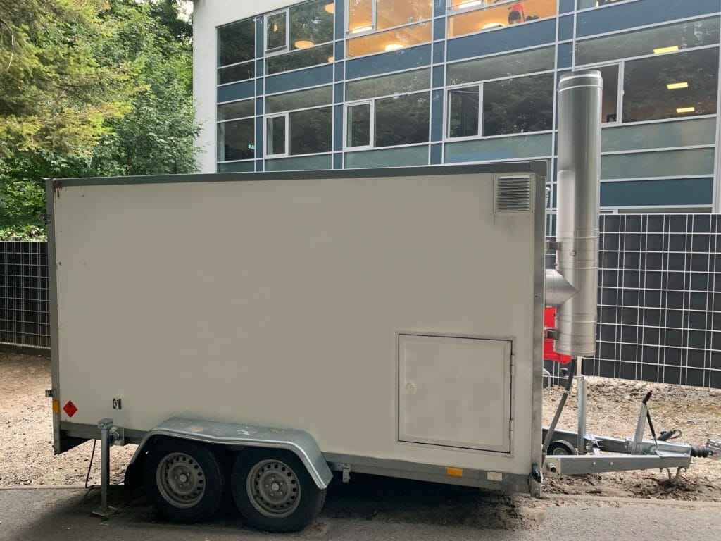 Mobile Heizzentrale im Betrieb vor einem Gebaeude
