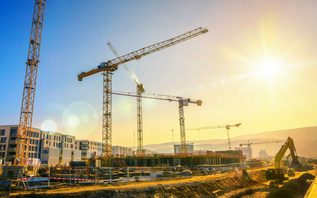 Nachhaltige Baustelle mit Baukranen und Arbeitsgeraeten in Sonnenuntergang