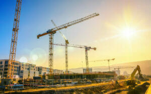 Nachhaltige Baustelle mit Baukranen und Arbeitsgeraeten in Sonnenuntergang