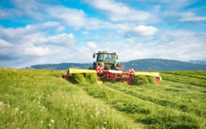 Traktor maeht Wiese zum Befuellen der Heutrocknungsanlage