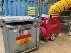 Roter 150 kW Bauheizer steht neben einem mobilen Oeltank auf einer Baustelle
