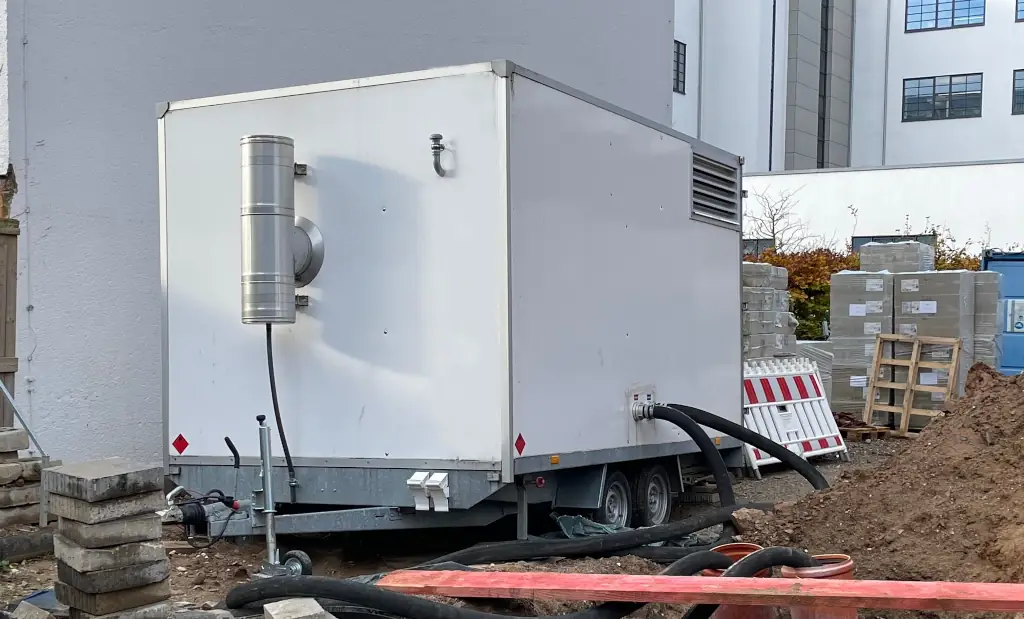 Mobile Heizzentrale neben einem Haus auf einer Baustelle